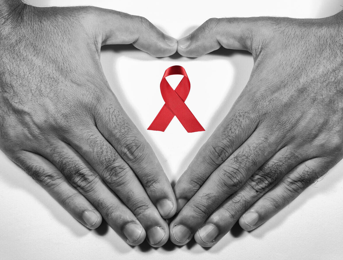 Man forming a heart with his hands and a red ribbon for the fight against AIDS on a white background.