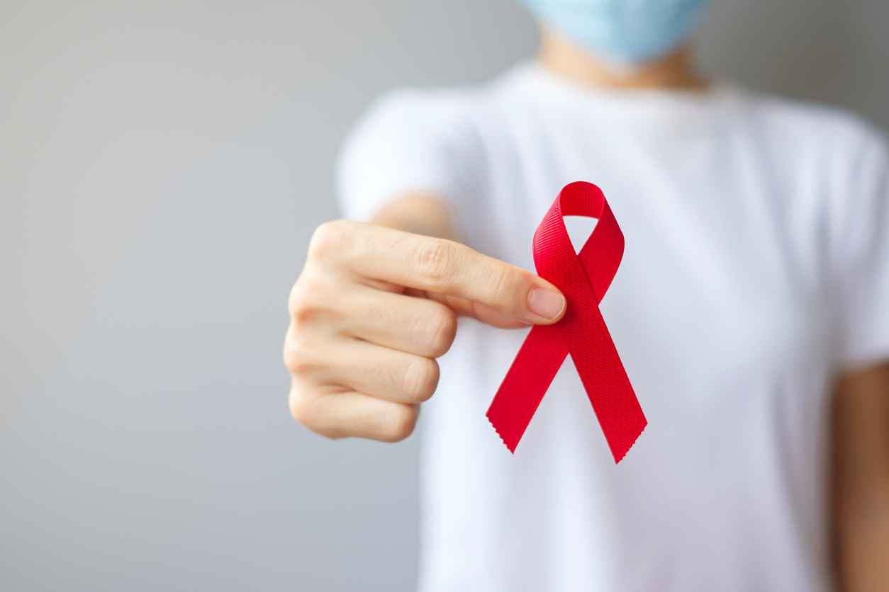 Hand holding Red Ribbon for December World Aids Day (acquired immune deficiency syndrome), multiple myeloma Cancer Awareness month and National Red ribbon week.