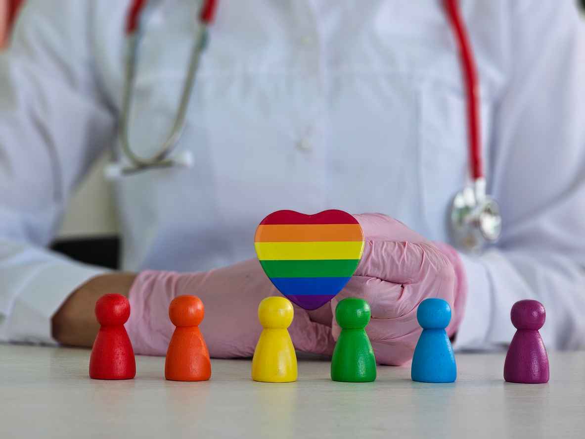 Doctor holding a heart with LGBT and people flag. Healthcare charity, insurance and medicine concept