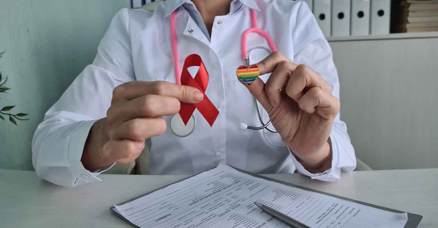 Stop AIDS and HIV and doctor concept. Red ribbon on heart with LGBT pride flag in clinic